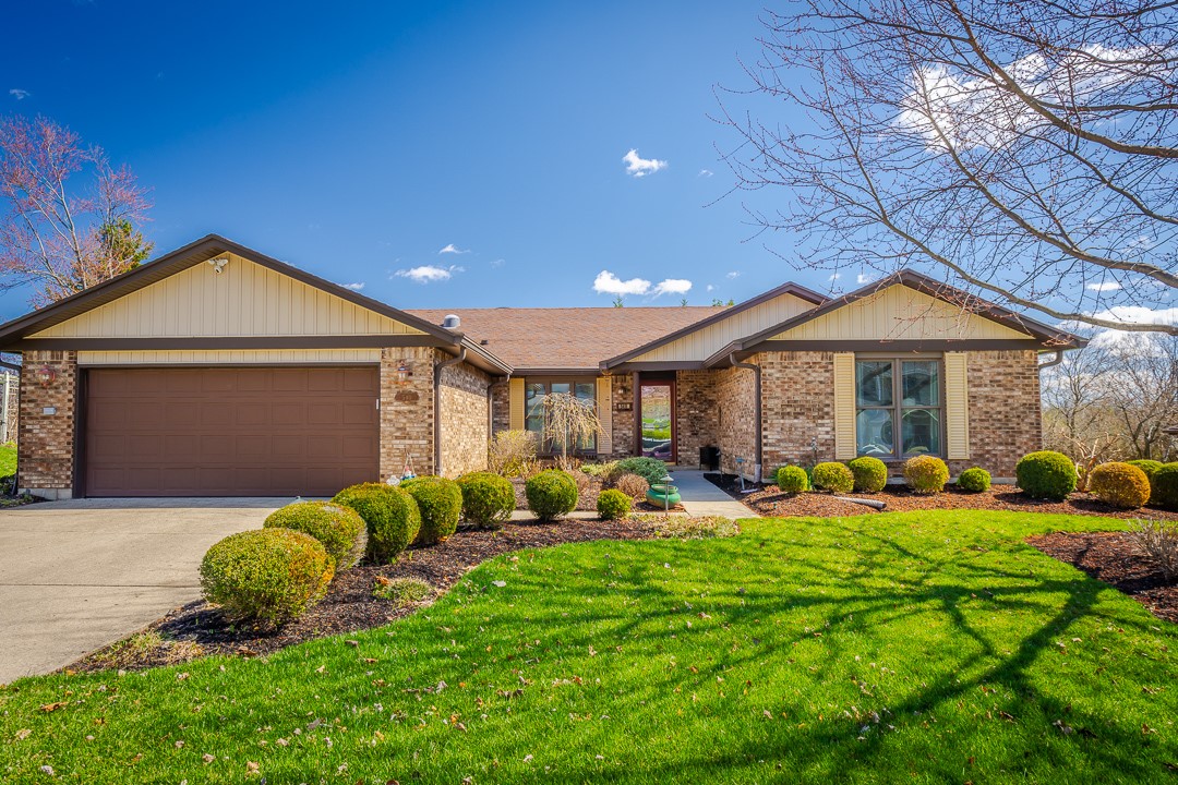 This charming home offers a spacious front yard and a classic brick exterior under a clear blue sky.