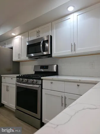 a kitchen with stainless steel appliances granite countertop a sink a stove and microwave
