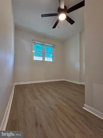 an empty room with wooden floor chandelier fan and windows
