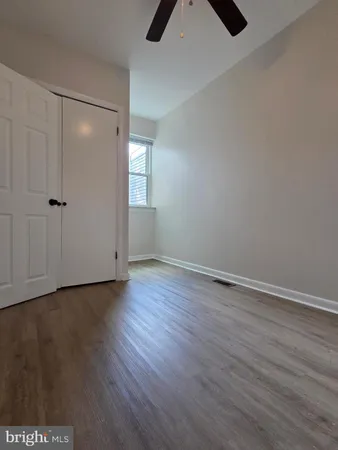 a view of an empty room with window and hardwood floor