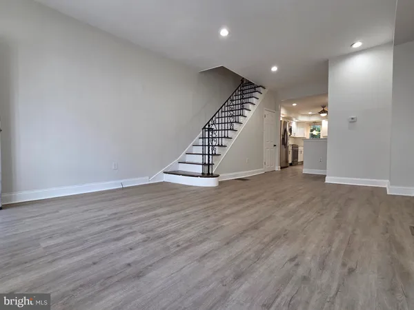 a view of an empty room with wooden floor and stairs