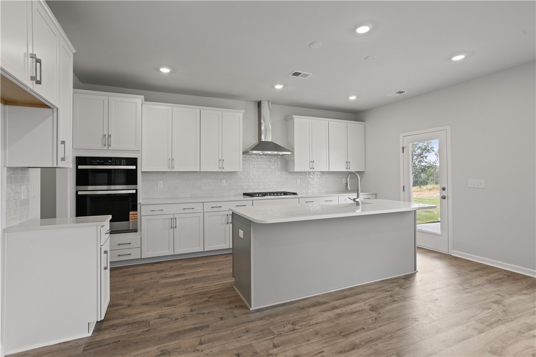 555 Hydrangea Street, Unit LOT 47 Seneca, SC 29678 - Photo 11 of 38 Modern kitchen with abundant cabinetry, a spacious island, and wood flooring throughout.