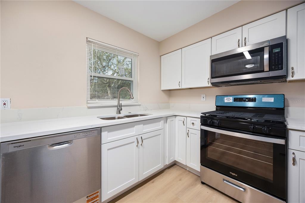 8013 Rhea Circle Orlando, FL 32807 - Photo 6 of 31 a kitchen with stainless steel appliances a stove microwave and sink