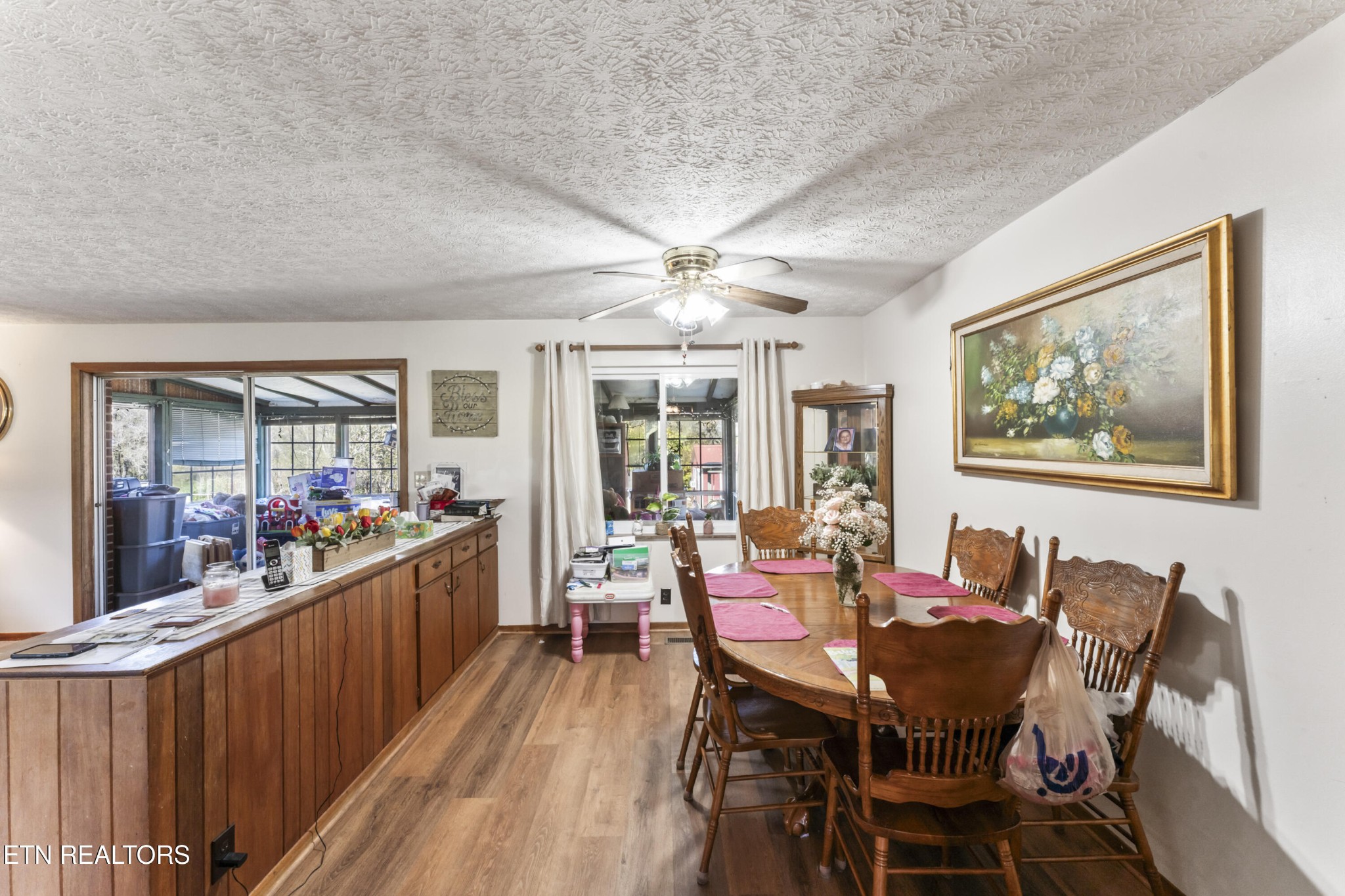 3856 Niles Ferry Road Greenback, TN 37742 - Photo 16 of 44 a view of a dining room and livingroom with furniture wooden floor a rug a flat screen tv a painting and a chandelier