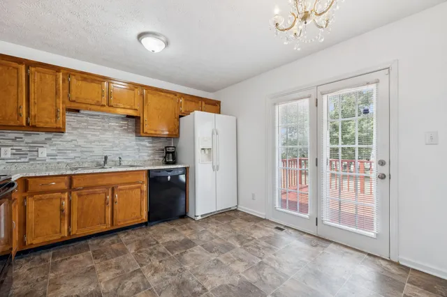 a kitchen with stainless steel appliances granite countertop a refrigerator a sink dishwasher a stove with wooden cabinets and floor