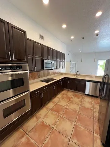 a large kitchen with kitchen island granite countertop a stove and a sink