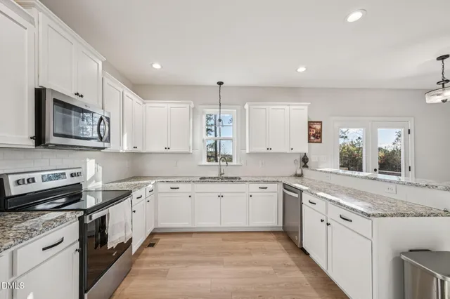 a large kitchen with stainless steel appliances granite countertop a stove sink and cabinets