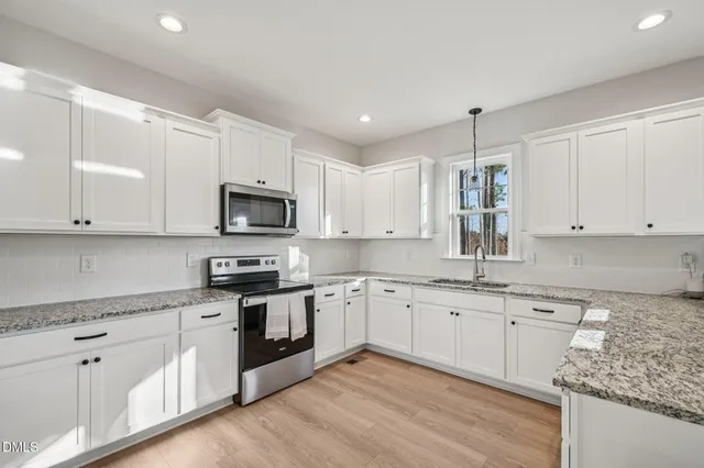 a kitchen with granite countertop white cabinets and white appliances