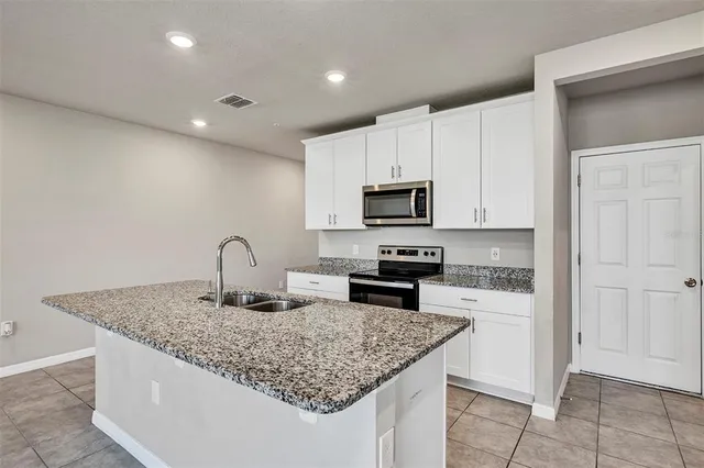 a kitchen with stainless steel appliances kitchen island granite countertop a sink a stove a microwave and cabinets