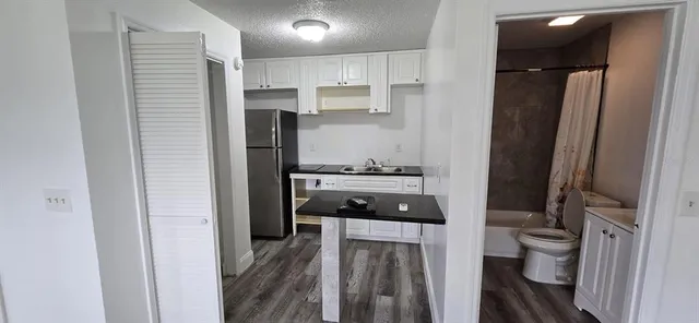a kitchen with a refrigerator and white cabinets