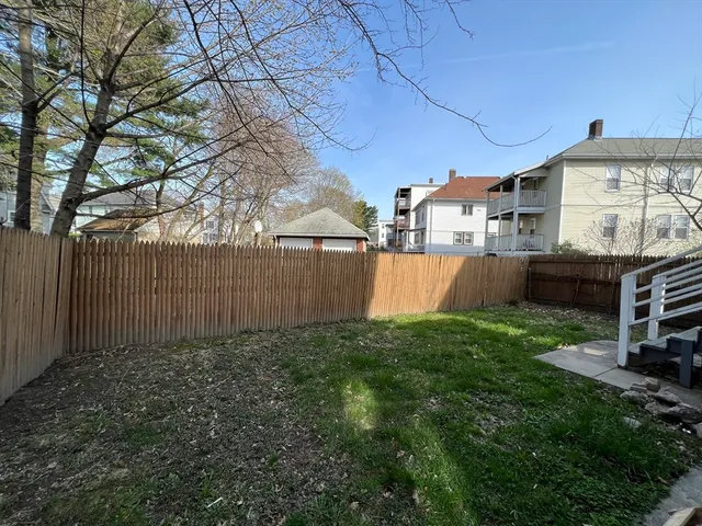 a view of backyard with barbeque grill and wooden fence