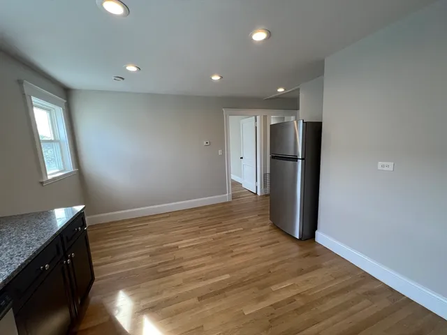 a view of a kitchen with a refrigerator and wooden floor