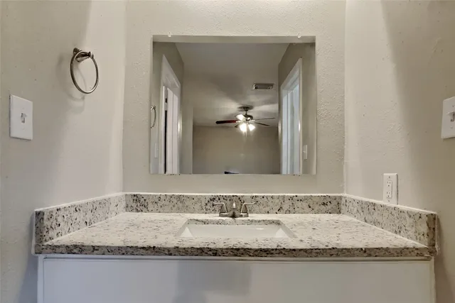 a bathroom with a granite countertop sink and a mirror