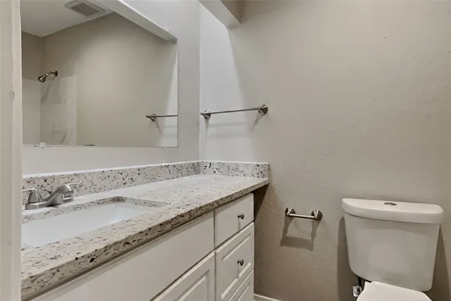 a bathroom with a granite countertop sink a toilet and a mirror