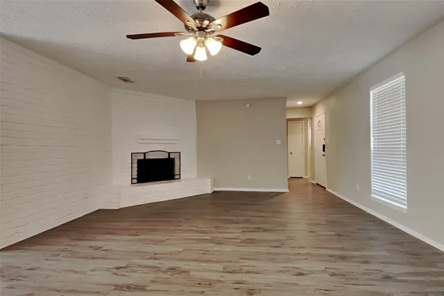 a view of an empty room with window and wooden floor