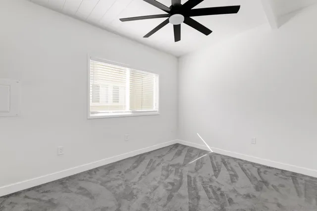 an empty room with a window and a fan