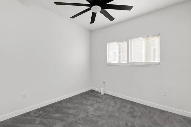 an empty room with a window and a fan
