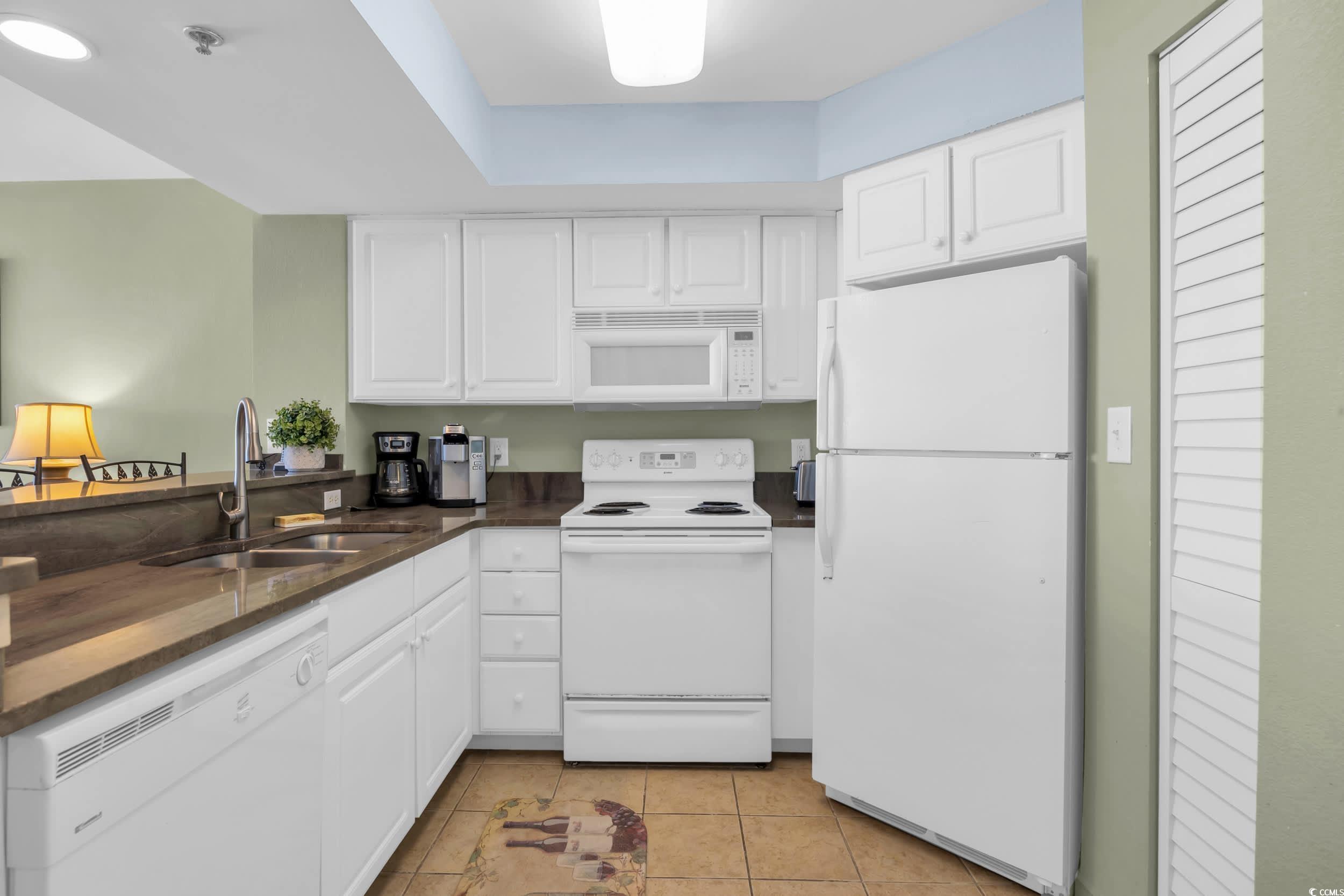 2504 North Ocean Boulevard, Unit 1234 Myrtle Beach, SC 29577 - Photo 9 of 22 Kitchen featuring white appliances, white cabinets, light tile patterned floors, and dark stone countertops