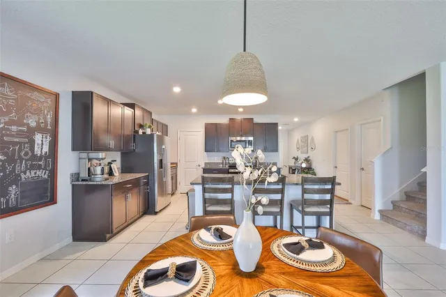 a kitchen with stainless steel appliances granite countertop a stove top oven a sink a dining table and chairs with wooden floor