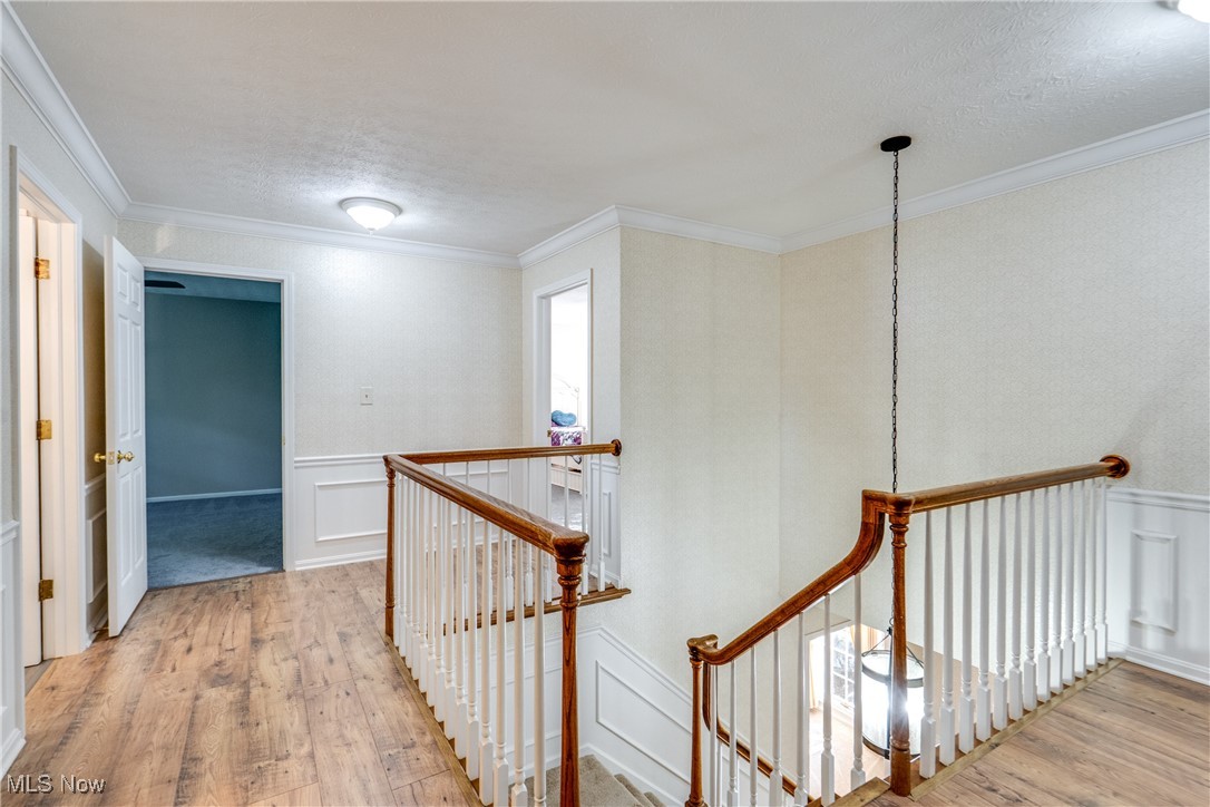 3465 Bancroft Road Akron, OH 44333 - Photo 43 of 50 Hall with an upstairs landing, hardwood / wood-style flooring, a decorative wall, wainscoting, and crown molding