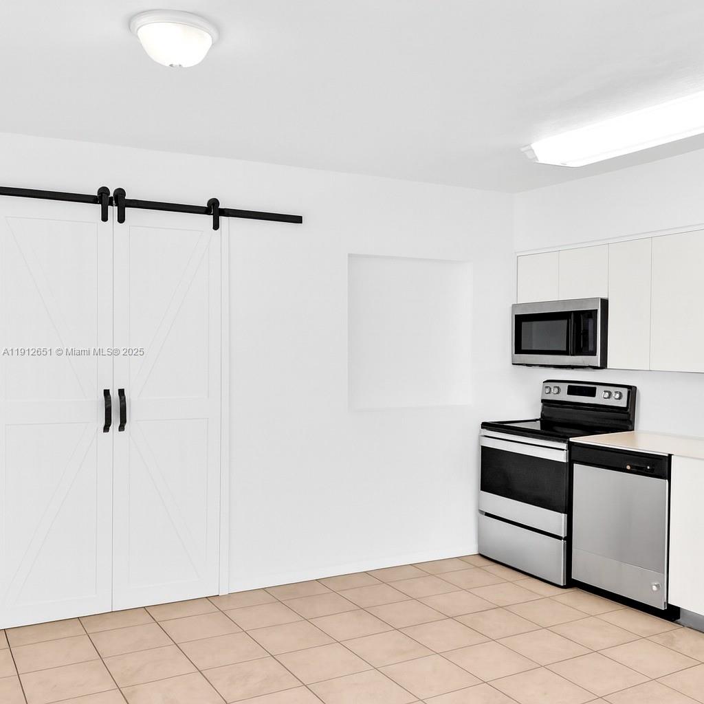 3415 Southwest 15th Street, Unit 2 Miami, FL 33145 - Photo 4 of 11 a kitchen with stainless steel appliances a sink a stove a microwave and white cabinets