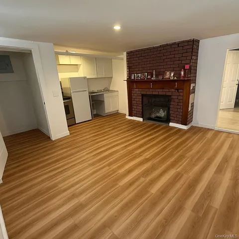 a view of kitchen and empty room with wooden floor