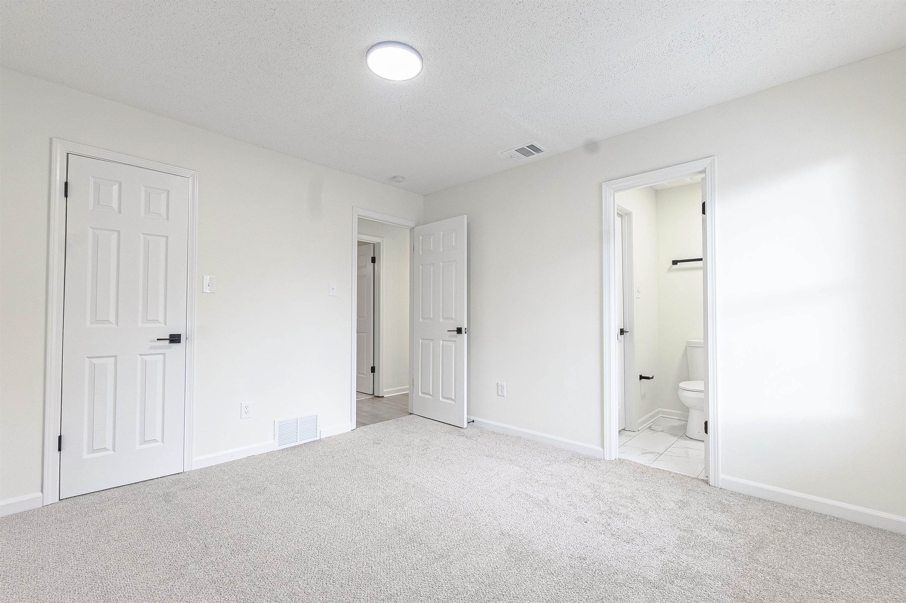 6538 Castle Ridge Cove Memphis, TN 38141 - Photo 16 of 27 Unfurnished bedroom featuring light carpet, a textured ceiling, ensuite bath, and a closet