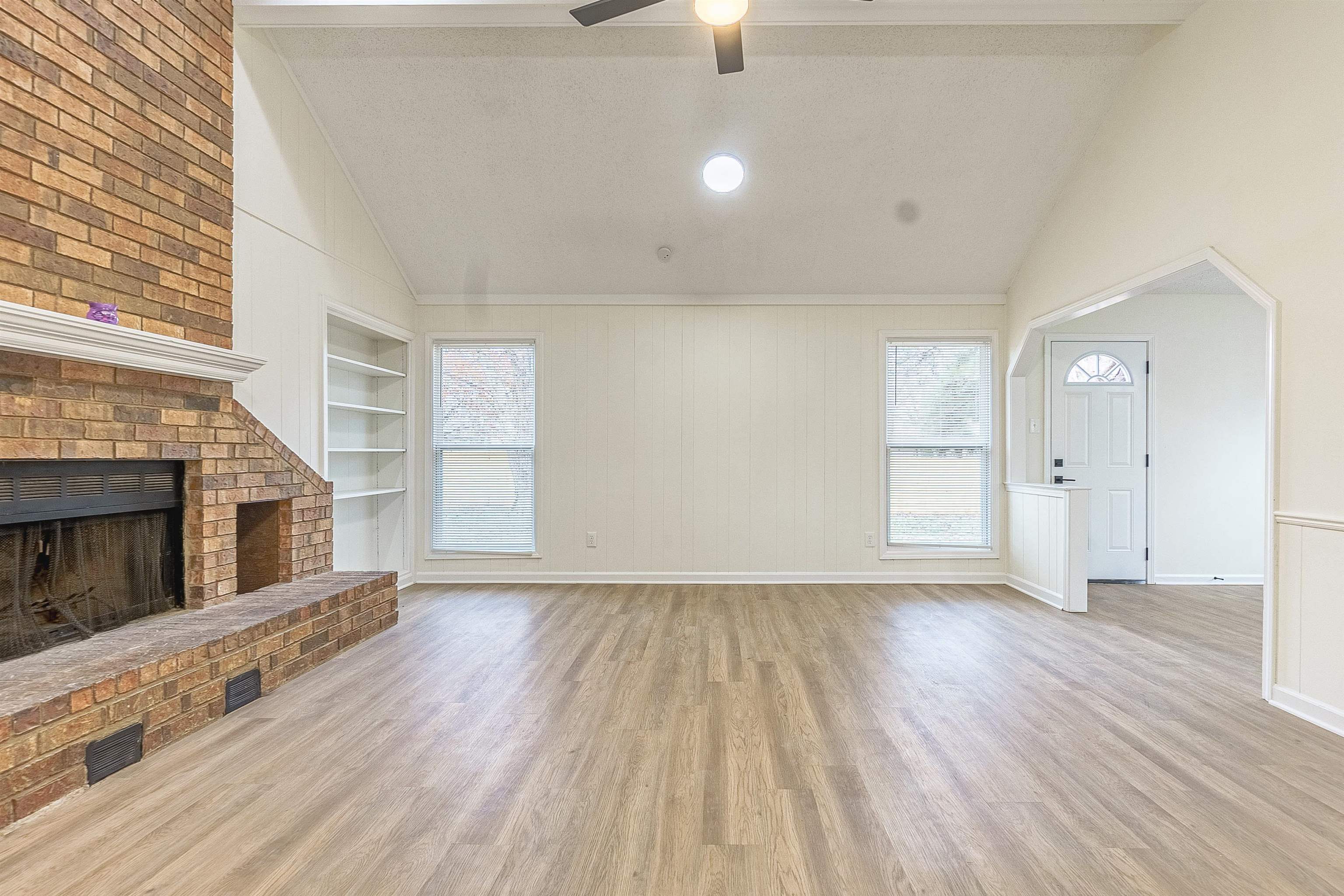 6538 Castle Ridge Cove Memphis, TN 38141 - Photo 8 of 27 Unfurnished living room with a fireplace, built in shelves, light hardwood / wood-style floors, and vaulted ceiling