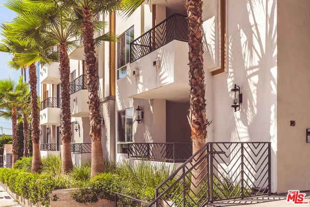 a view of a brick wall with plants and large trees