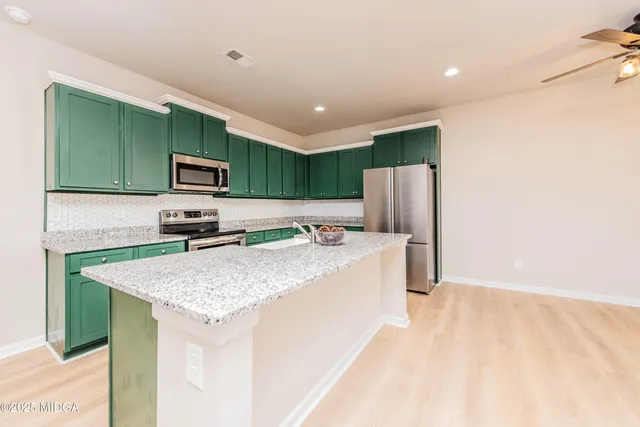 a kitchen with kitchen island a sink stainless steel appliances and cabinets