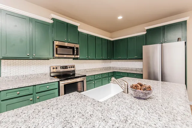 a kitchen with stainless steel appliances kitchen island granite countertop a refrigerator and a sink