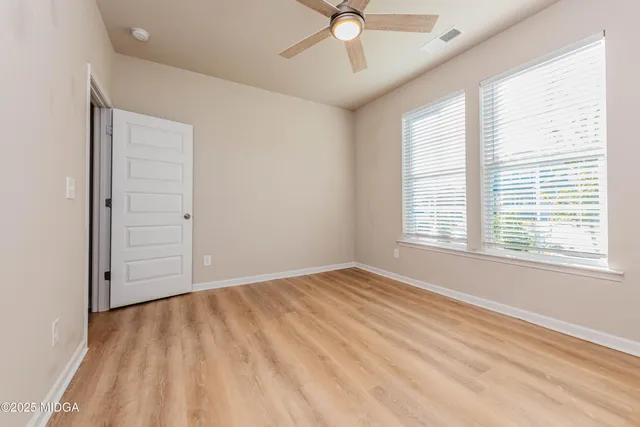 a view of an empty room with a window and wooden floor