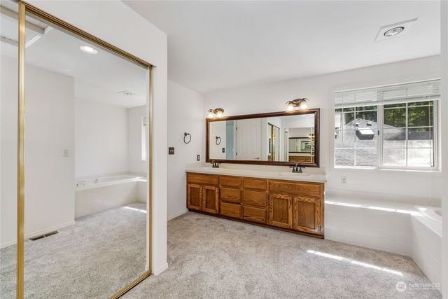 a spacious bathroom with a tub sink and mirror