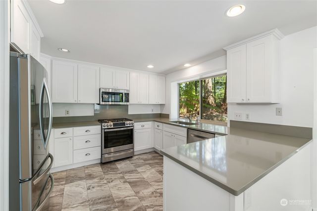 a kitchen with stainless steel appliances granite countertop a stove a sink and a refrigerator