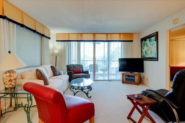 a living room with furniture a flat screen tv and a floor to ceiling window