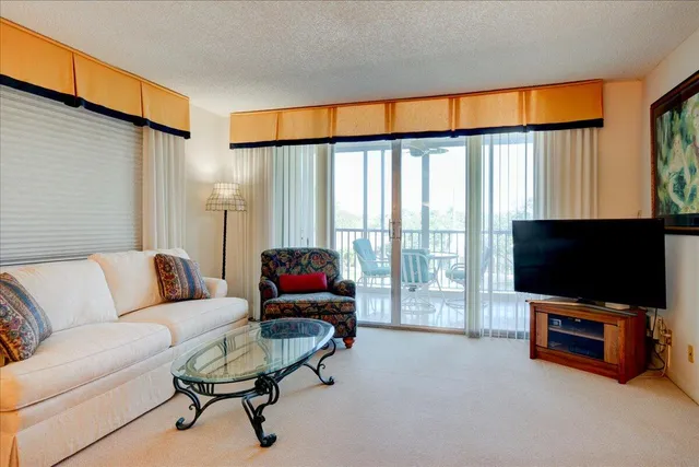 a living room with furniture a flat screen tv and a floor to ceiling window