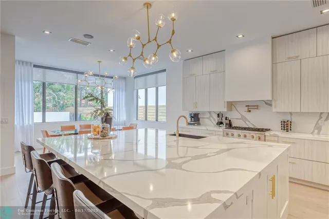 a kitchen with kitchen island granite countertop a sink a stove a dining table and chairs