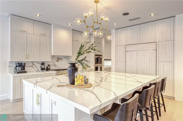 a kitchen with kitchen island a chandelier dining table and chairs