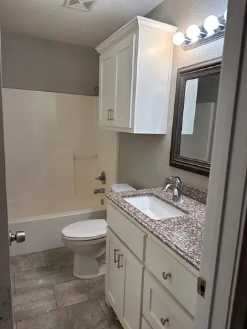 a bathroom with a granite countertop sink toilet and mirror