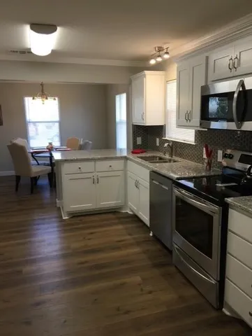 a kitchen with stainless steel appliances granite countertop a stove a sink and a microwave