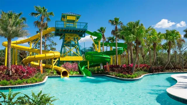 a view of yellow house with a yard and potted plants