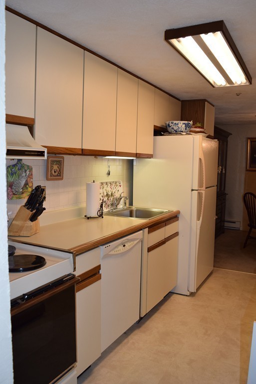 140 Swanson Road, Unit 413 Boxborough, MA 01719 - Photo 8 of 26 a kitchen with a refrigerator and cabinets