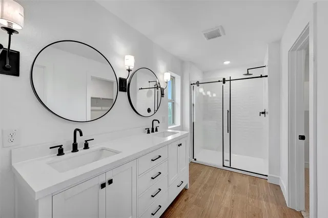 a bathroom with a double vanity sink mirror and hallway