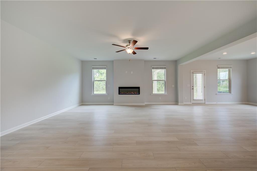 709 Dunlake Way Locust Grove, GA 30248 - Photo 13 of 34 an empty room with chandelier fan and windows