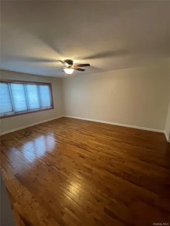 a view of an empty room with window and wooden floor