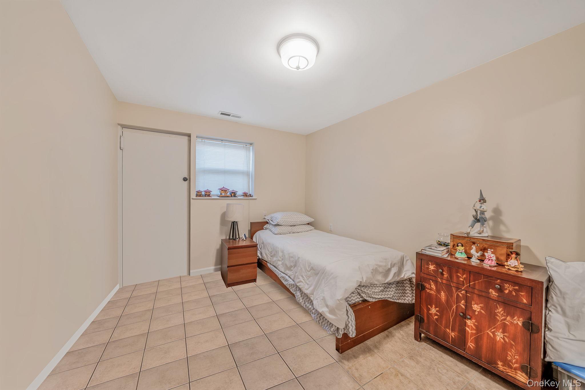 20-23 Whitestone Expressway Queens, NY 11357 - Photo 24 of 28 a bedroom with a bed and a lamp on the dresser