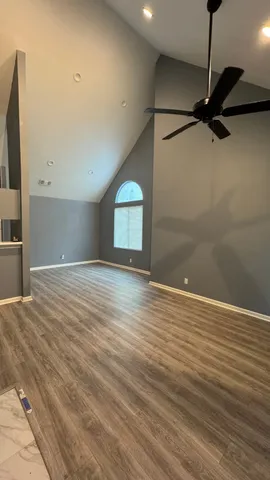 a view of a room with a ceiling fan and wooden floor
