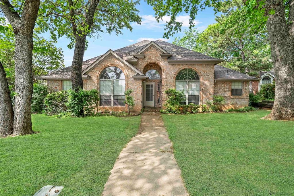 a front view of a house with a garden and trees