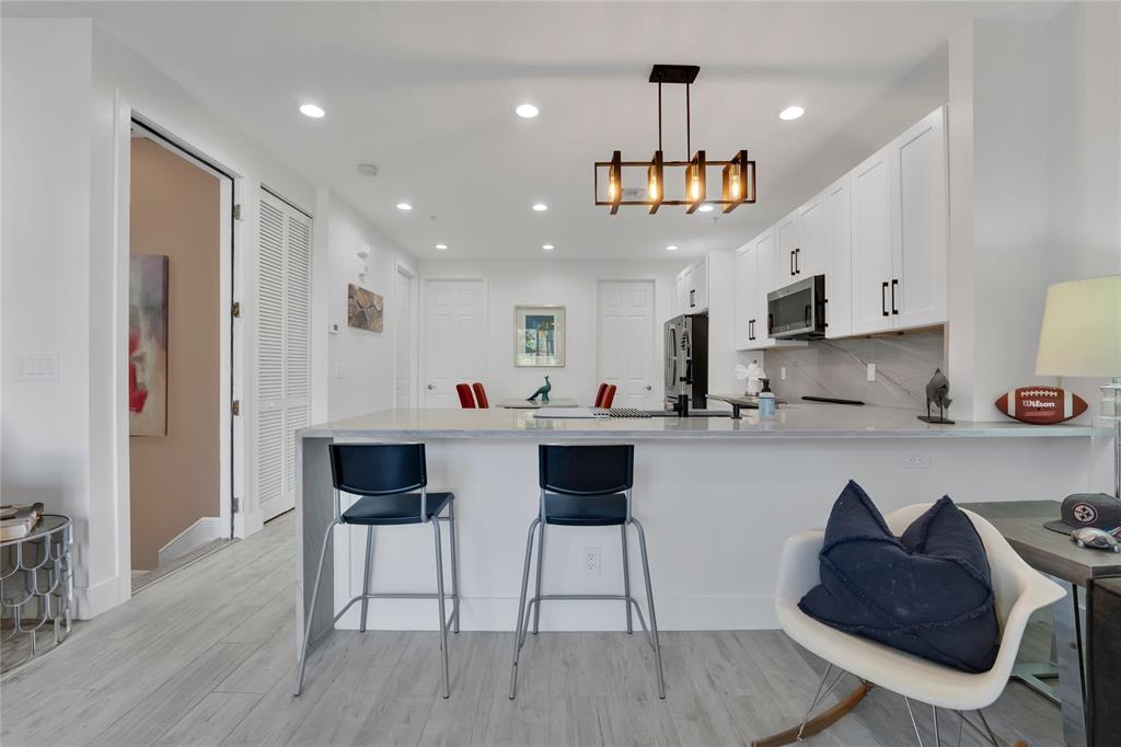 142 Morning Dew Circle, Unit 142 Jupiter, FL 33458 - Photo 11 of 34 a kitchen with stainless steel appliances kitchen island granite countertop a wooden floor and white cabinets