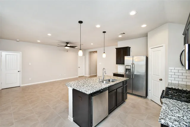 a kitchen with granite countertop a sink refrigerator and cabinets